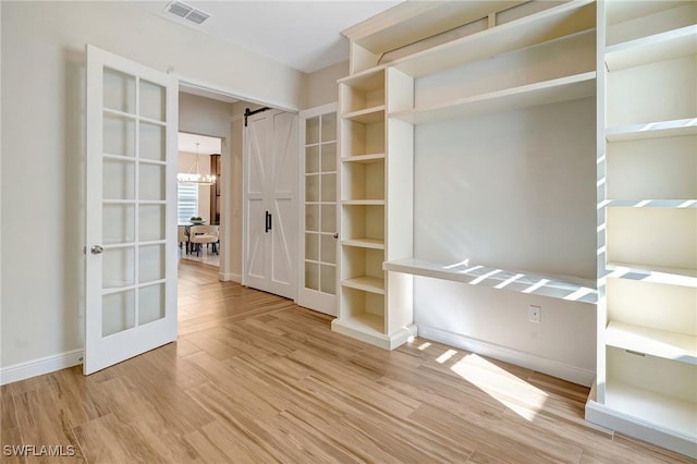 empty room with visible vents, baseboards, light wood-style floors, and an inviting chandelier