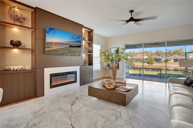 living room with a glass covered fireplace, a ceiling fan, and marble finish floor