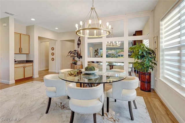 dining space featuring a notable chandelier, visible vents, baseboards, and light wood finished floors