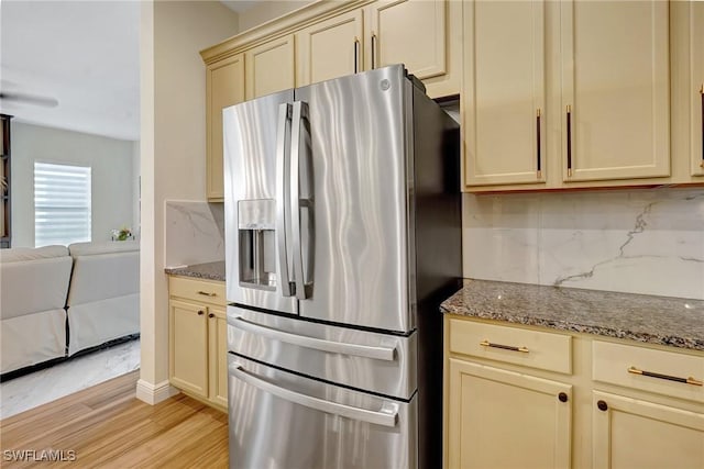 kitchen with decorative backsplash, dark stone countertops, cream cabinets, and stainless steel fridge with ice dispenser