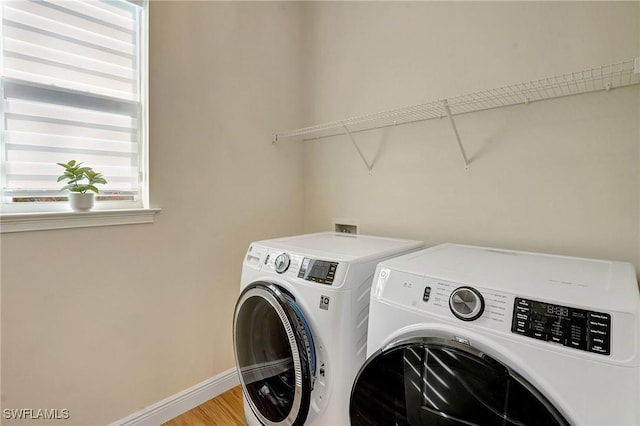 washroom with washing machine and clothes dryer, laundry area, light wood-style flooring, and baseboards