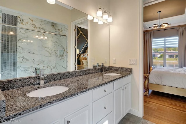 full bath with double vanity, a marble finish shower, ensuite bathroom, and a sink