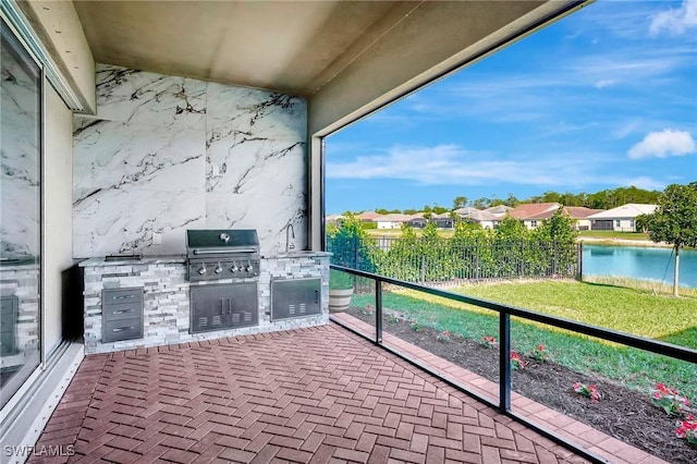 balcony with exterior kitchen, a water view, a residential view, and grilling area