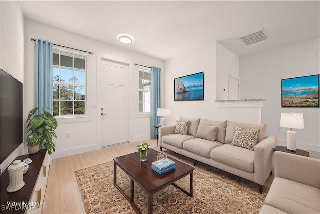 living room with wood finished floors, visible vents, and baseboards