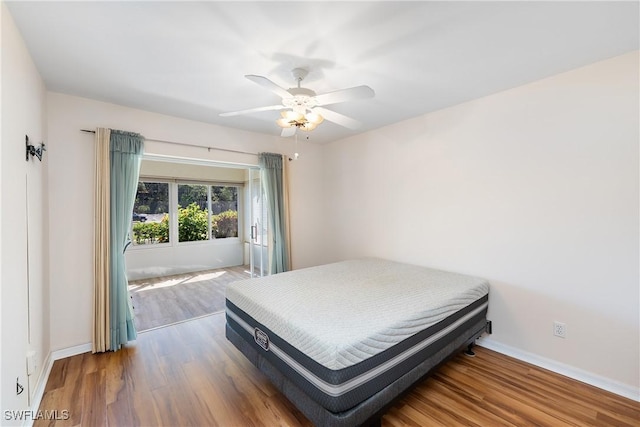 bedroom featuring baseboards, wood finished floors, and a ceiling fan