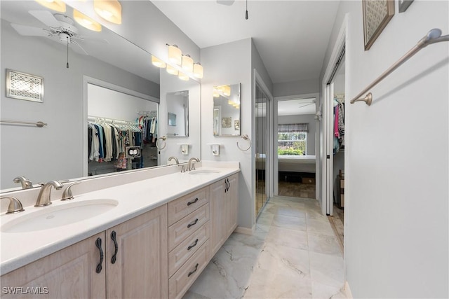 full bathroom featuring ceiling fan, a spacious closet, marble finish floor, and a sink