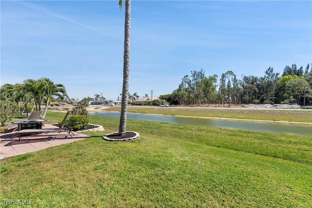 view of yard with a water view, a patio, and an outdoor fire pit