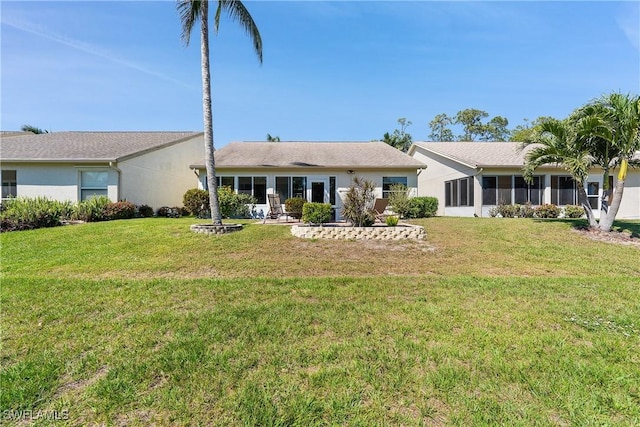 rear view of house featuring stucco siding and a lawn