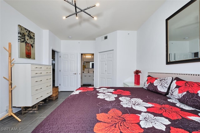 bedroom with a notable chandelier, visible vents, connected bathroom, and dark tile patterned flooring