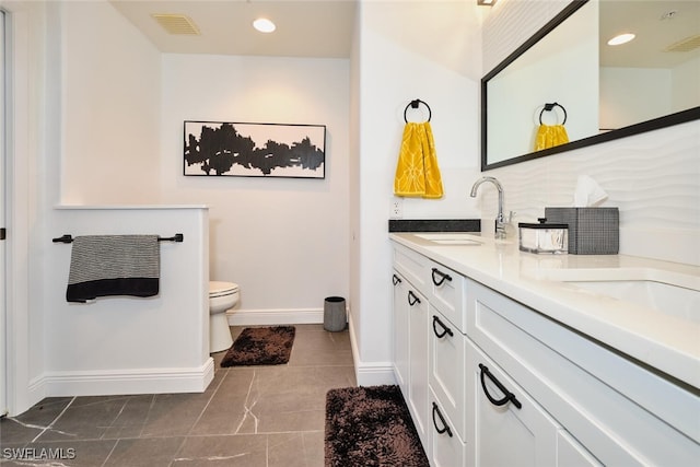 bathroom with a sink, visible vents, baseboards, and double vanity