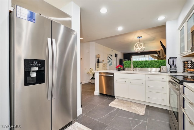 kitchen featuring dark tile patterned floors, light countertops, white cabinets, stainless steel appliances, and a sink