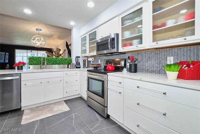 kitchen featuring decorative backsplash, a sink, white cabinetry, stainless steel appliances, and glass insert cabinets