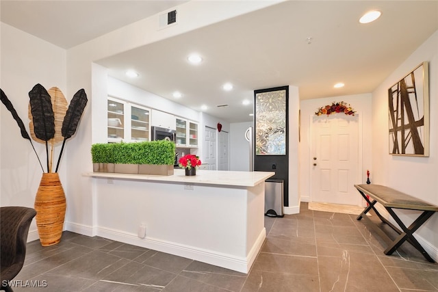 kitchen with stainless steel microwave, recessed lighting, a peninsula, and visible vents