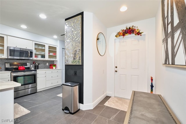 kitchen with tasteful backsplash, recessed lighting, appliances with stainless steel finishes, white cabinets, and glass insert cabinets