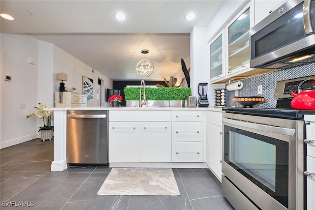 kitchen featuring a sink, backsplash, appliances with stainless steel finishes, a peninsula, and white cabinets