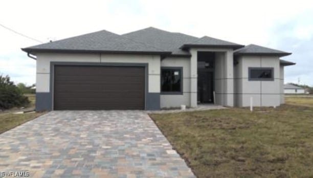 prairie-style house with a garage, decorative driveway, and a front yard