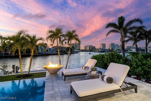 view of patio with a water view, a fire pit, and a view of city