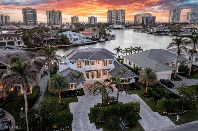 aerial view at dusk featuring a water view and a city view