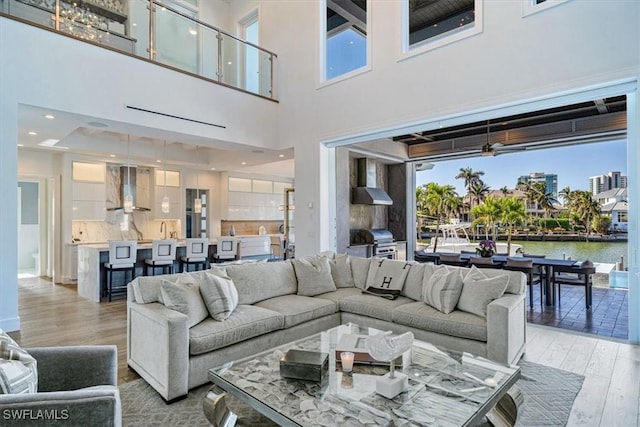 living room with recessed lighting, light wood-style floors, a water view, and a healthy amount of sunlight