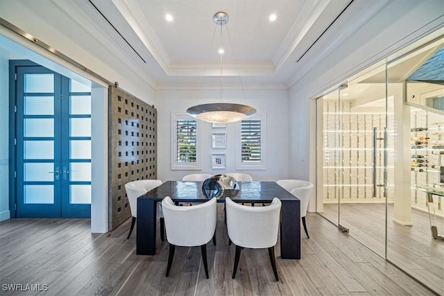 dining room featuring ornamental molding, french doors, a tray ceiling, and wood finished floors