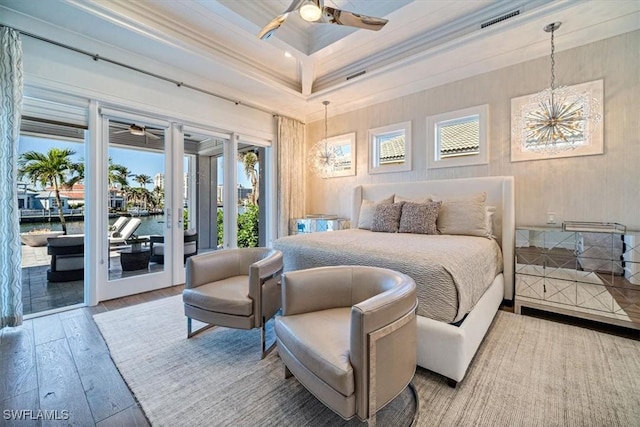 bedroom with access to exterior, visible vents, a tray ceiling, ornamental molding, and hardwood / wood-style floors