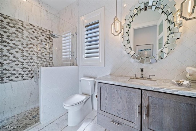 bathroom featuring toilet, marble finish floor, tile walls, walk in shower, and vanity