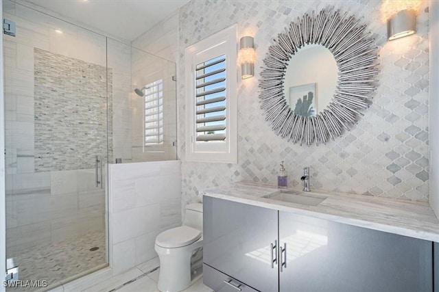 bathroom featuring vanity, a stall shower, tile walls, toilet, and tile patterned floors