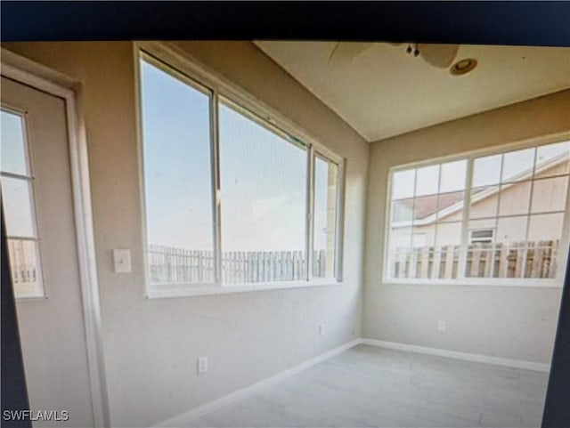 empty room featuring plenty of natural light, wood finished floors, and baseboards