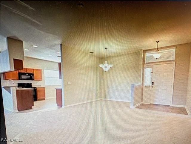 kitchen with brown cabinets, hanging light fixtures, black appliances, light colored carpet, and open floor plan