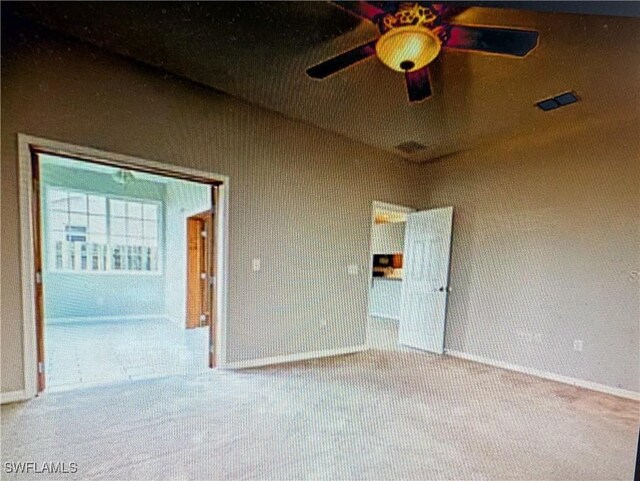 carpeted spare room featuring baseboards and ceiling fan