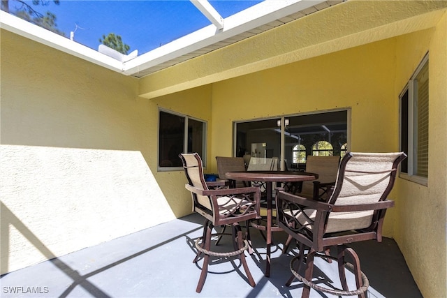 view of patio with glass enclosure and outdoor dining area