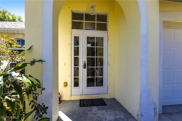 doorway to property with a garage, roof with shingles, and stucco siding