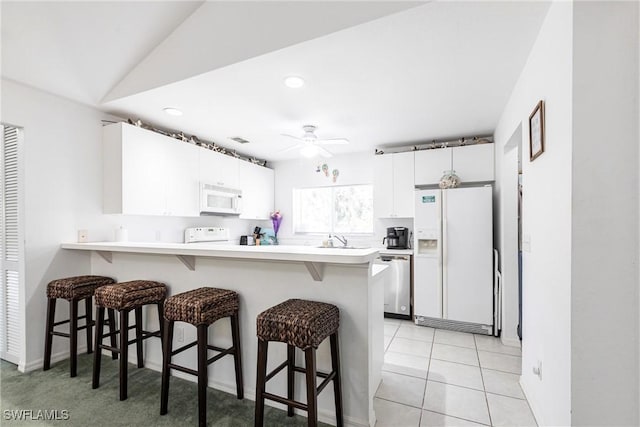 kitchen with white appliances, a breakfast bar, a peninsula, and light countertops