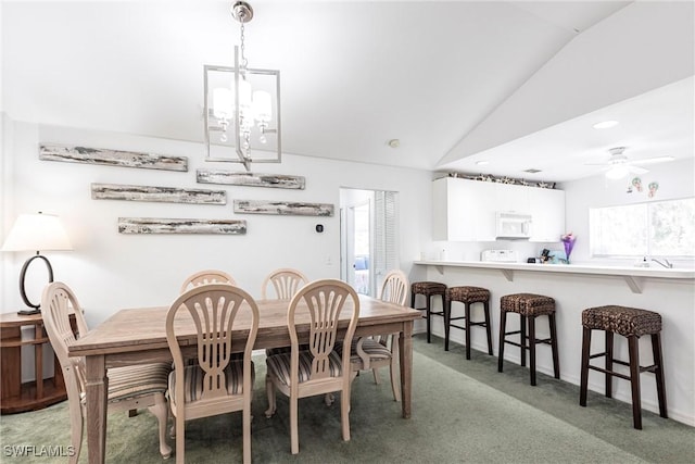 dining area with ceiling fan with notable chandelier, vaulted ceiling, plenty of natural light, and light colored carpet