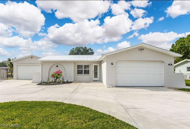 single story home featuring concrete driveway, metal roof, a garage, and stucco siding