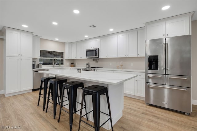 kitchen with a center island, a kitchen bar, recessed lighting, light wood-style floors, and stainless steel appliances