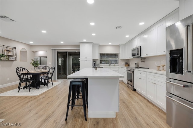 kitchen with visible vents, a kitchen island, light wood-style floors, and appliances with stainless steel finishes