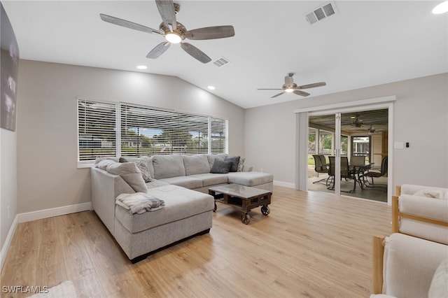 living area with visible vents, lofted ceiling, baseboards, and light wood-style flooring