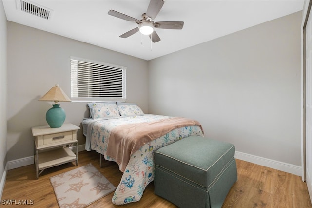 bedroom with ceiling fan, wood finished floors, visible vents, and baseboards