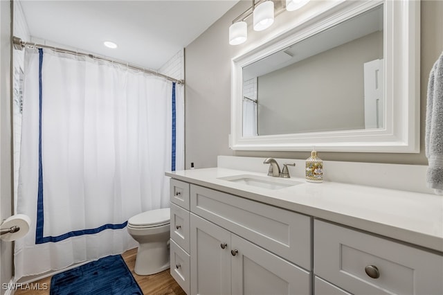 full bathroom featuring a shower with shower curtain, toilet, wood finished floors, and vanity