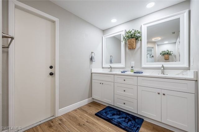 bathroom with double vanity, wood finished floors, baseboards, and a sink