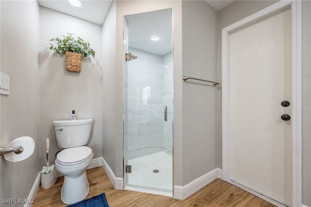 bathroom with toilet, wood finished floors, baseboards, and a marble finish shower