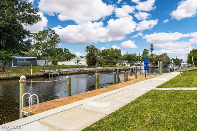 view of dock with a yard and a water view