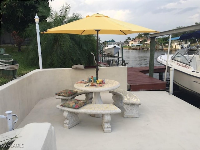 dock area with a water view, outdoor dining space, and a patio area