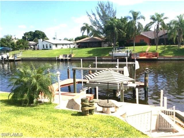 view of dock with boat lift, a yard, and a water view