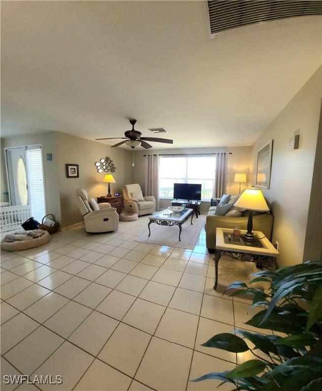 living room featuring light tile patterned floors, visible vents, and ceiling fan