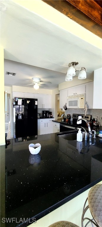 kitchen featuring white microwave, electric range, a peninsula, black fridge with ice dispenser, and white cabinets