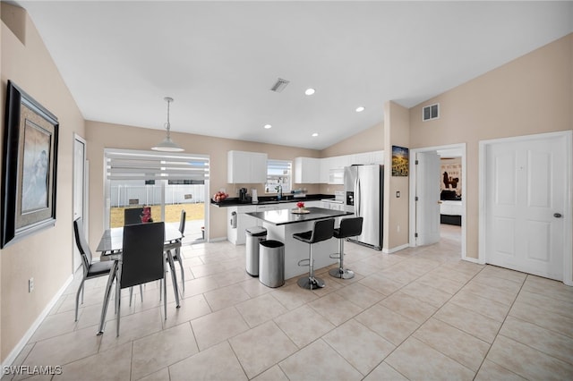 kitchen featuring visible vents, a center island, stainless steel refrigerator with ice dispenser, and a sink