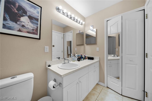 bathroom with toilet, vanity, and tile patterned flooring