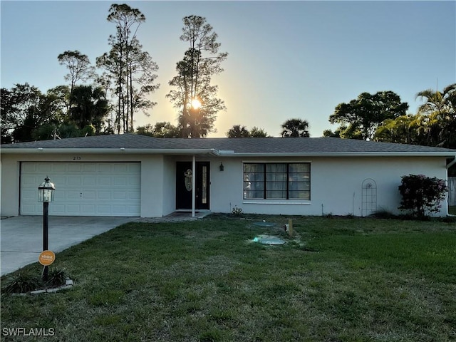 ranch-style house with stucco siding, a front yard, a garage, and driveway